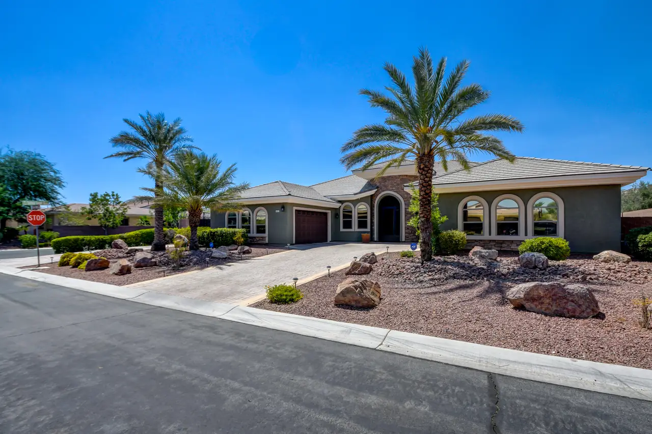 Wide view of the front yard with palms, boulders, the house set well back from the street