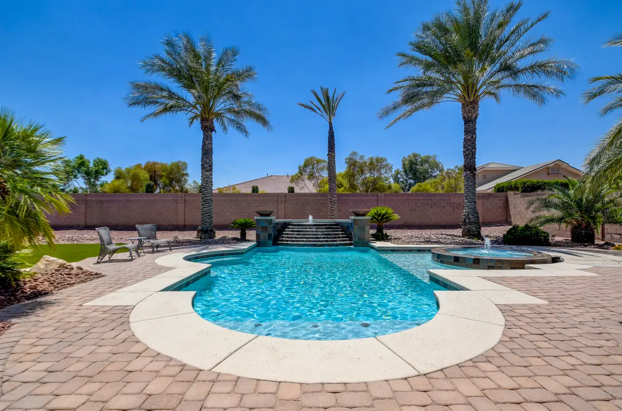 Pool and raised spa on pavers, with palms along the back wall