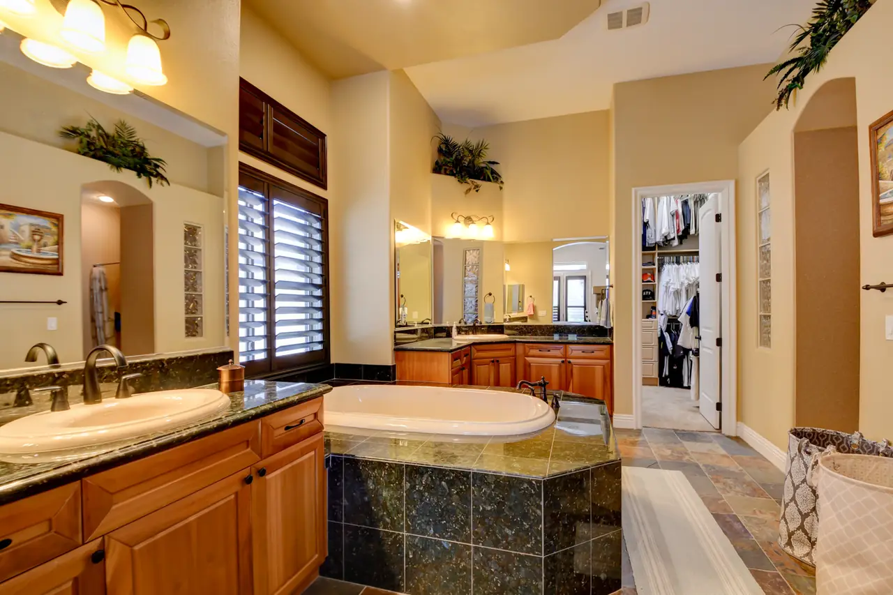 Primary bath with a jetted tub, dual vanities and granite counters